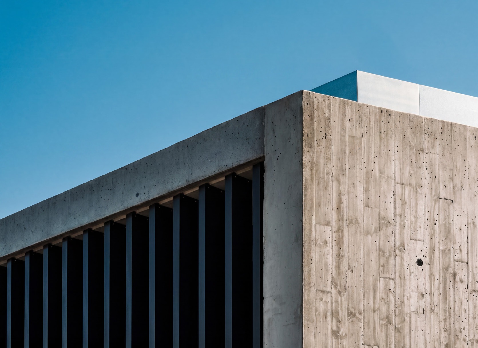 Sunlight on rhythmic concrete columns beneath a blue sky